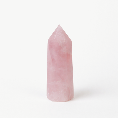 Rose quartz crystal tower with a polished pink point on a white background
