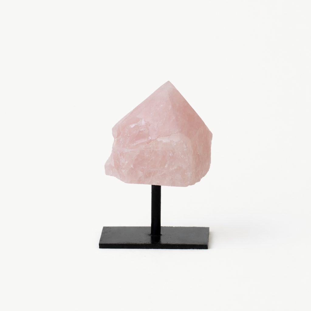 rose quartz crystal point mounted on a black metal display stand