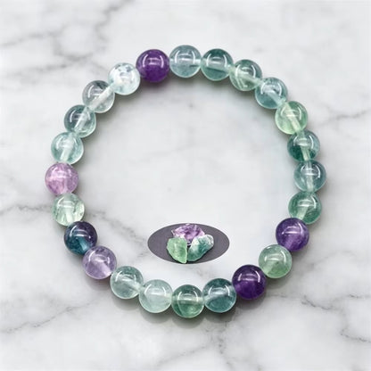 Fluorite Balance beaded bracelet with a carved stone charm on a white marble surface